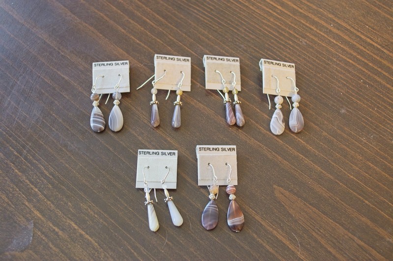 picture of an array of botswana agate teardrop and flattened teardrop shape earrings showing the differences in shades and banding of this stone.