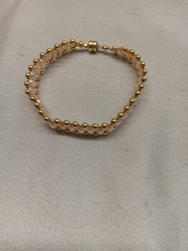 double woven style bracelet which results in a band of pearls with gold-filled beads forming the top and bottom of the band